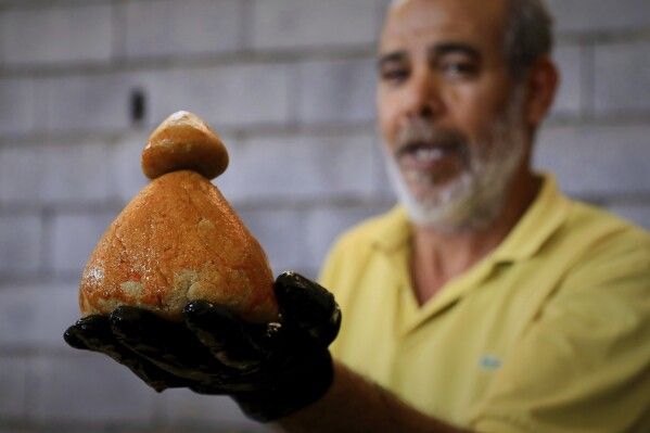 A Libyan volunteer shows a just made traditional unleavened Libyan bread made out of barley in Tajoura, east of Libya's capital Tripoli, Tuesday, March 11, 2025, during the Muslim holy month of Ramadan. (AP Photo/Yousef Murad)